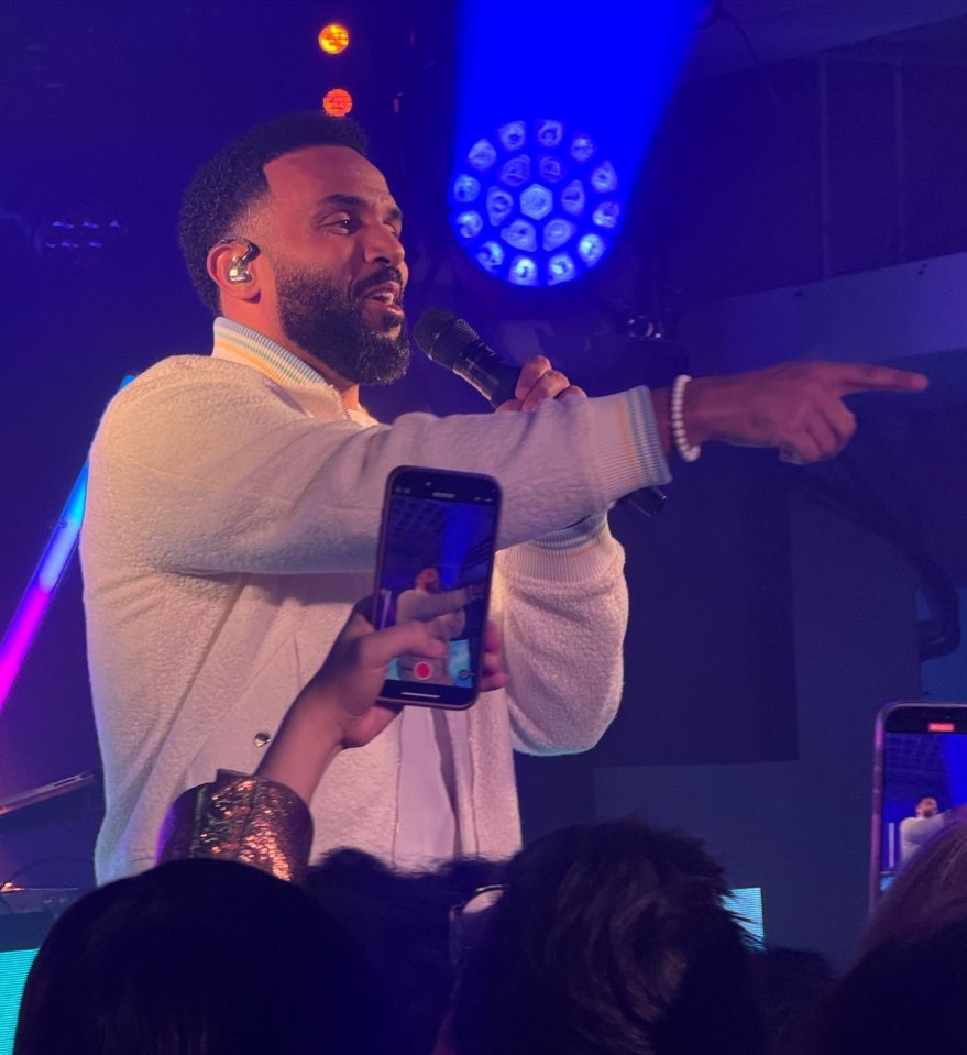 Man singing into a microphone and pointing.
