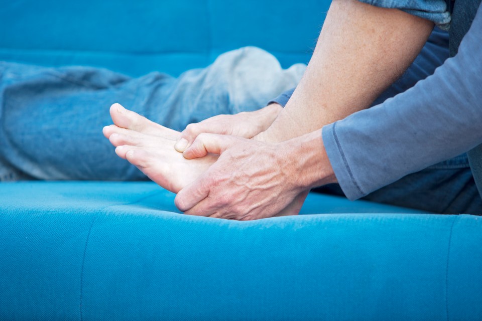 Man holding his left foot in pain.