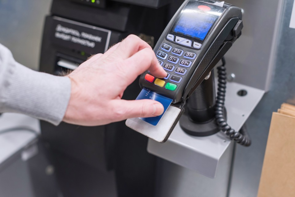 Man using credit card at self-service checkout.