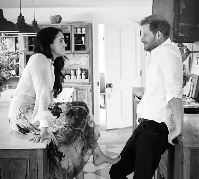 Black and white photo of Meghan Markle and Prince Harry in a kitchen.