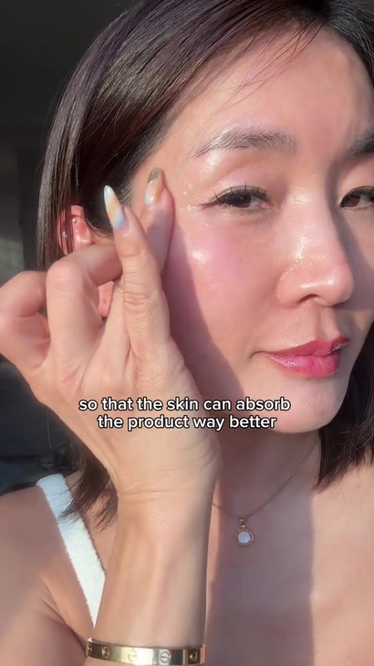 Woman applying skincare product to her face.
