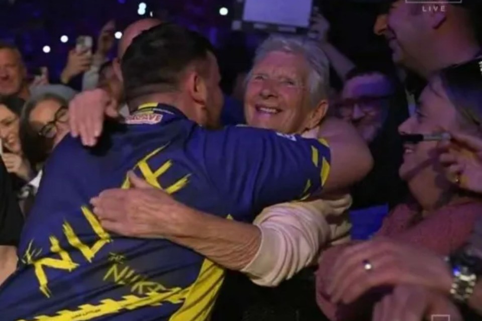 An image collage containing 1 images, Image 1 shows An elderly woman hugging a man in a blue jersey