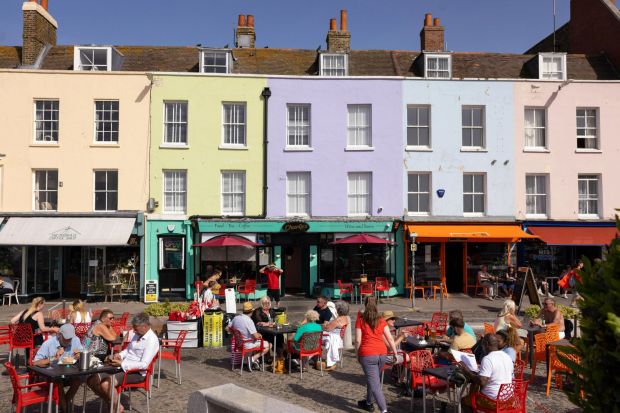 An image collage containing 1 images, Image 1 shows Patrons sitting at outdoor tables in front of colorful buildings in Margate, UK