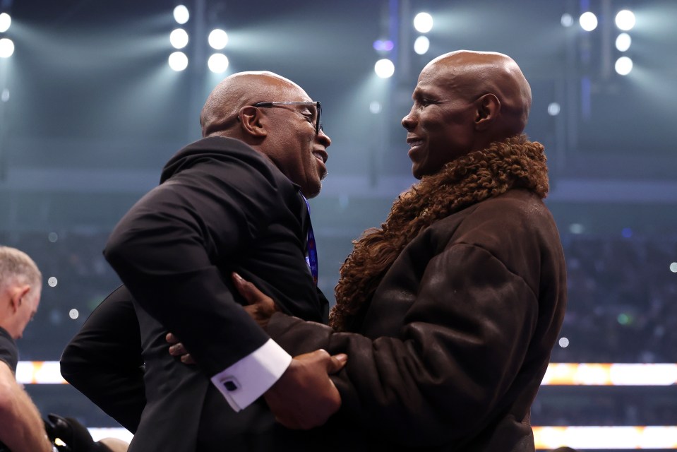 Nigel Benn and Chris Eubank embracing in a boxing ring.