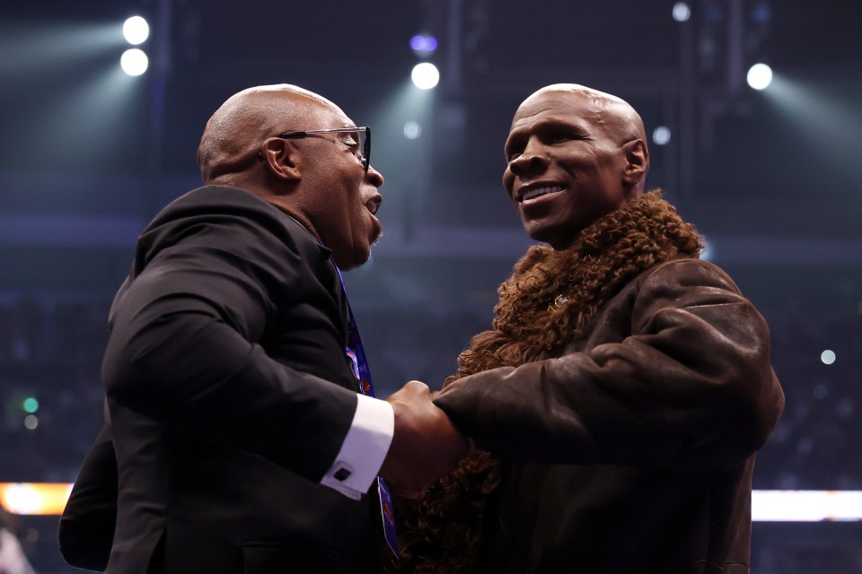 Nigel Benn and Chris Eubank shaking hands in a boxing ring.