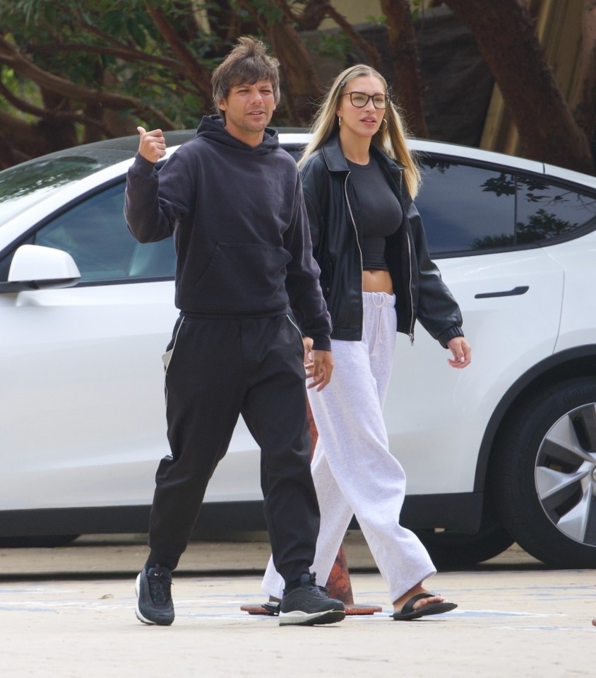 Louis Tomlinson and Zara McDermott holding hands while walking.