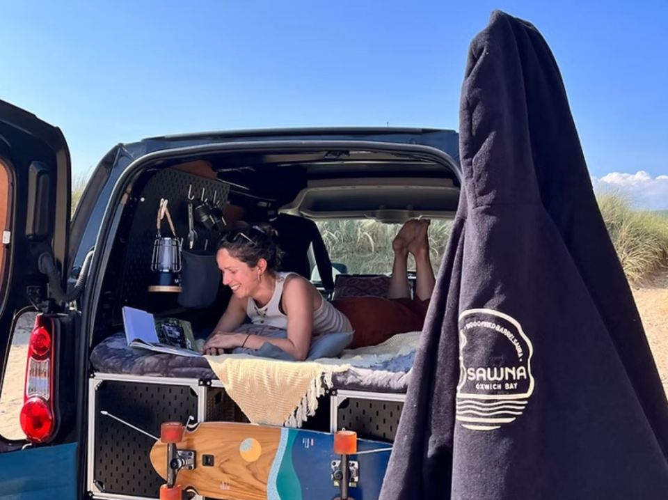 Woman relaxing in a camper van, reading a book.