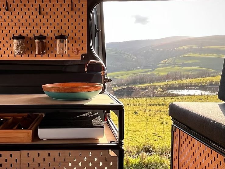 Van conversion camper kitchen with sink and scenic view.