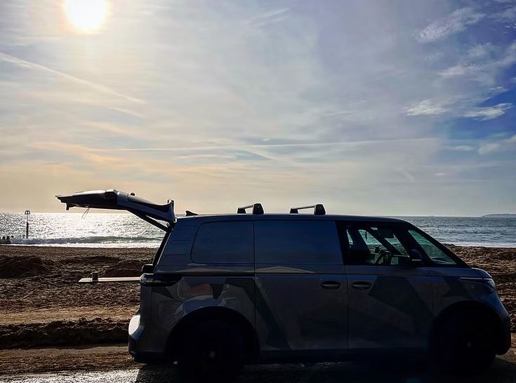 Camper van parked on a beach with its tailgate open.