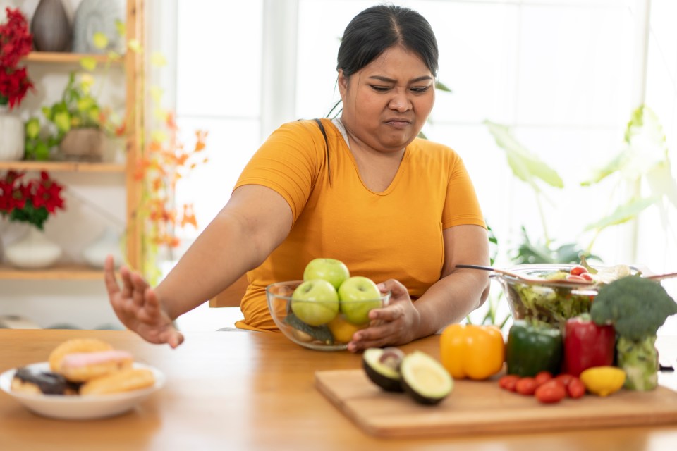 Overweight woman choosing healthy food over unhealthy food.