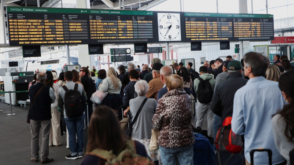 Passengers queueing to board high-speed trains at a station.