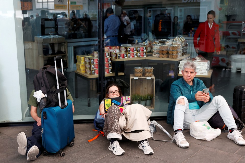 Passengers sitting on the floor of a train station during a power outage.
