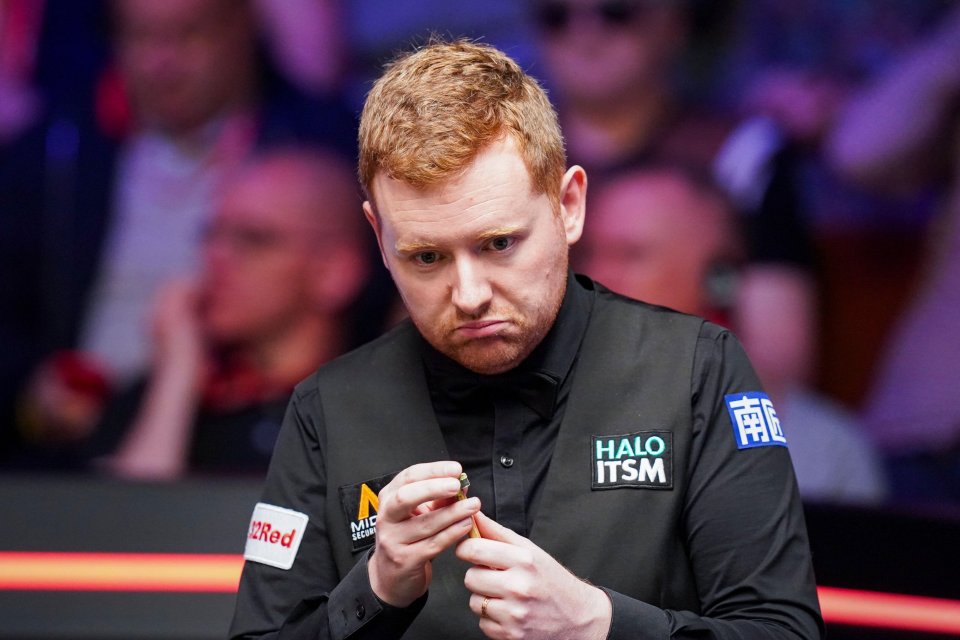 Ben Woollaston chalking his cue during a snooker match.