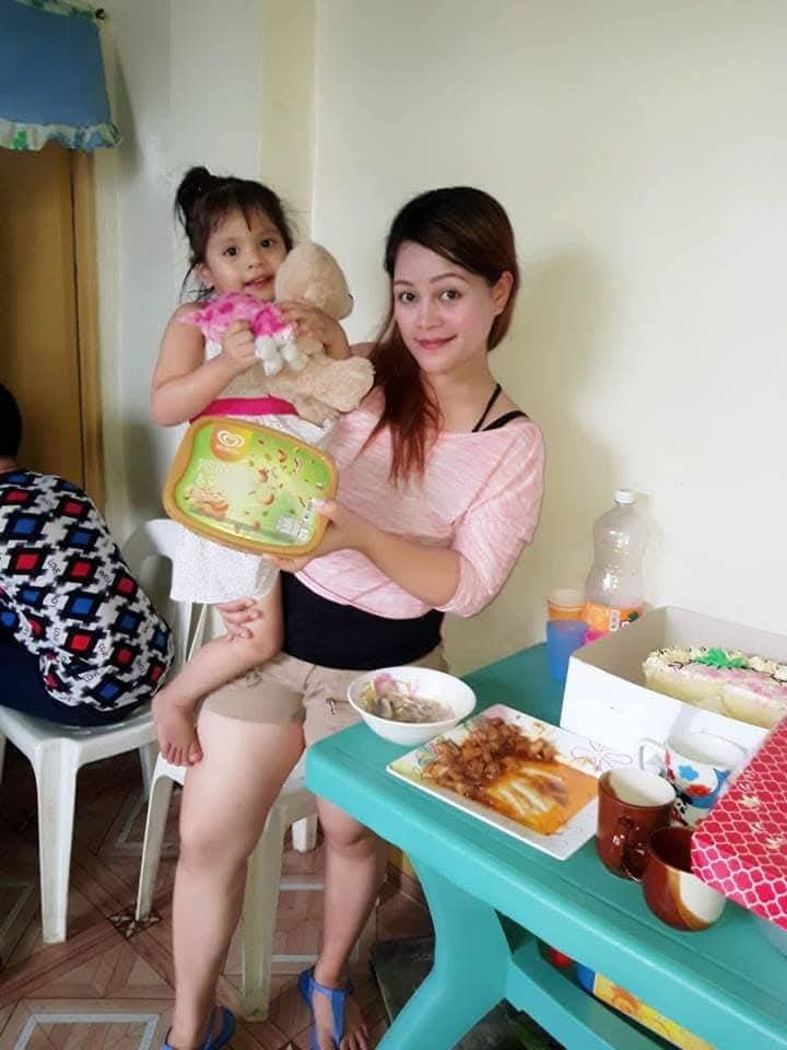 Woman holding a young child and a container of ice cream.