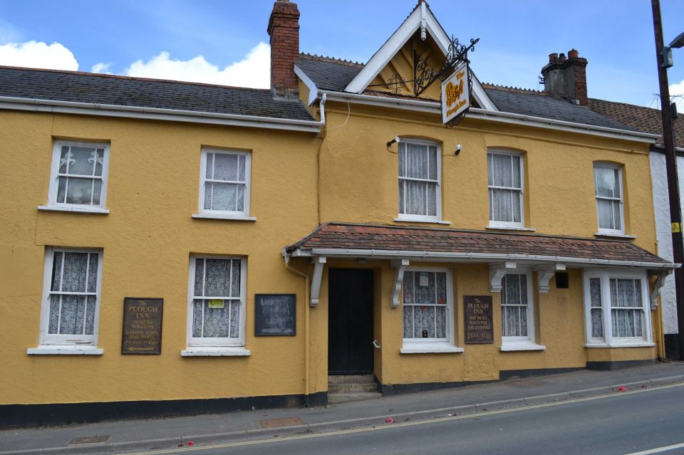 The Plough Inn, a yellow building with white windows and signage.