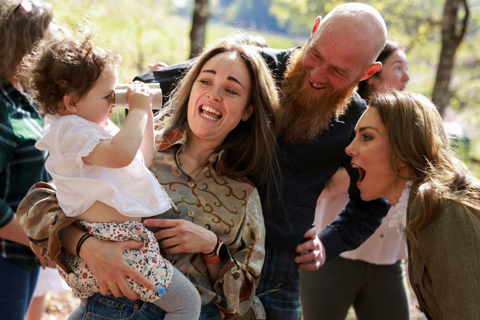 The Princess of Wales interacting with a young child and adults in a forest.