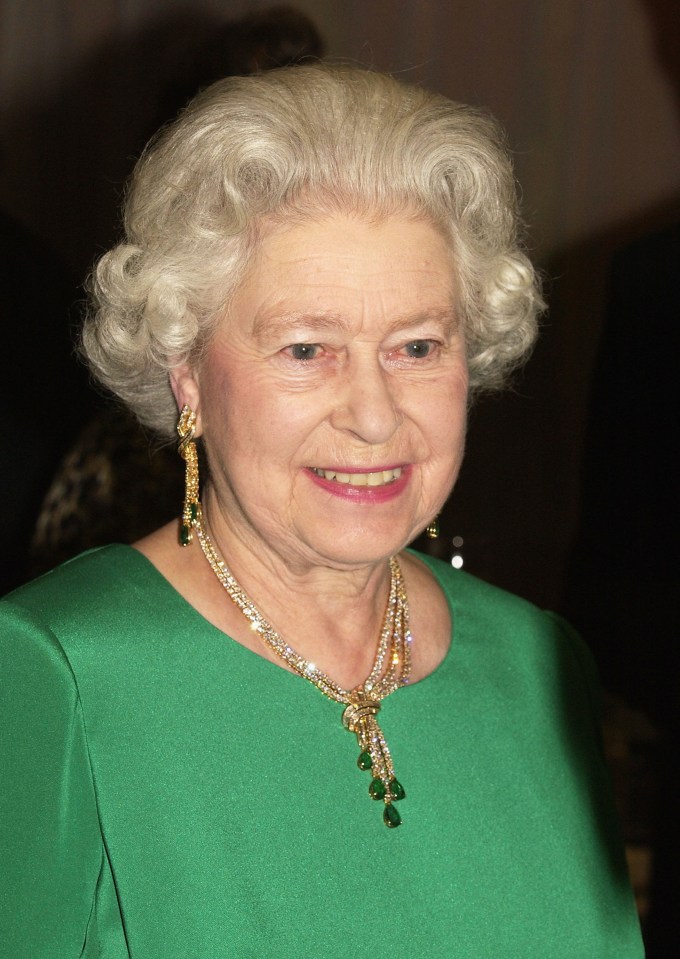 Queen Elizabeth II at a royal gala wearing a green dress and jewelry.