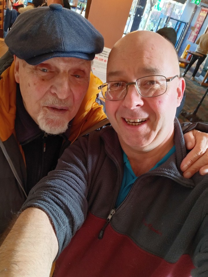 Selfie of two men, one wearing a newsboy cap.