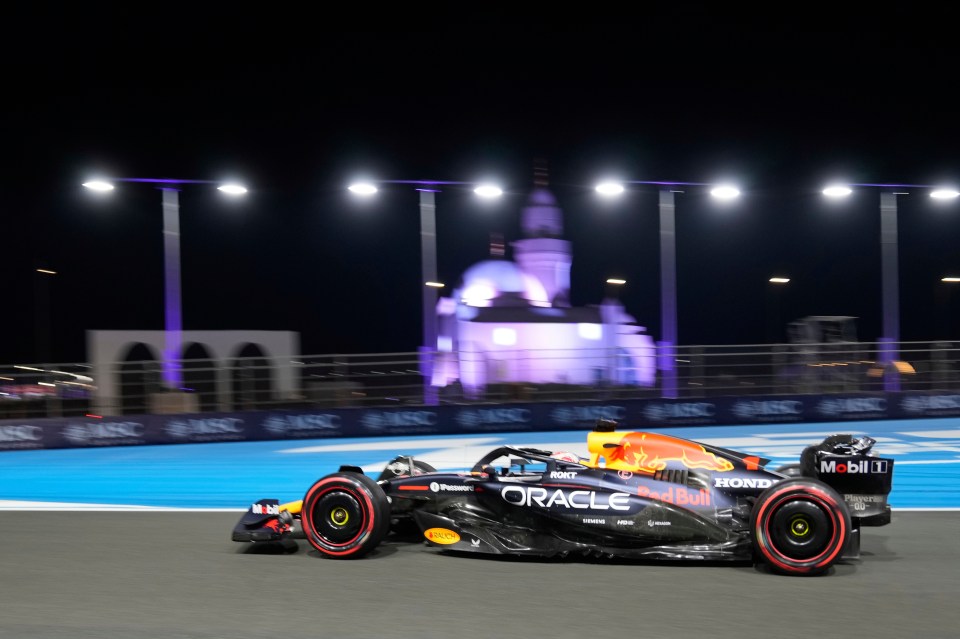Max Verstappen's Red Bull car speeding on a racetrack at night.