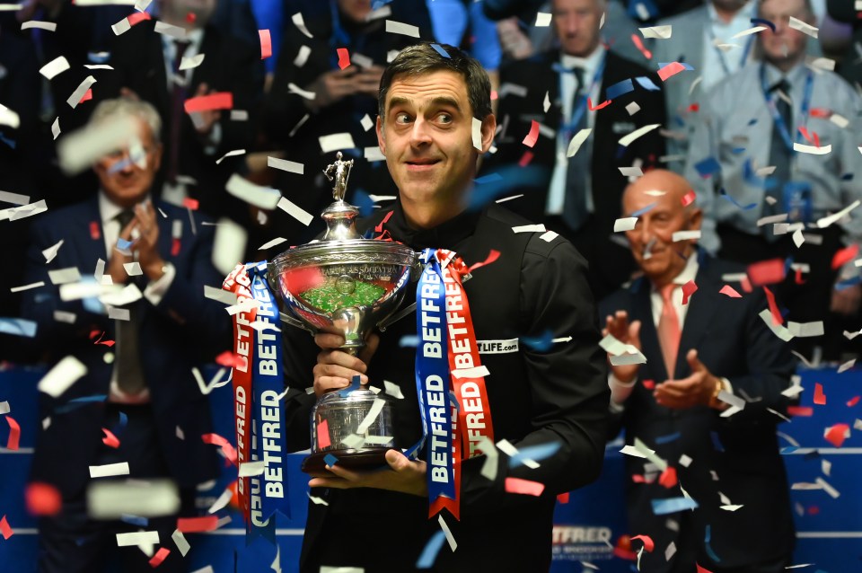 Ronnie O'Sullivan holding a snooker championship trophy amidst confetti.