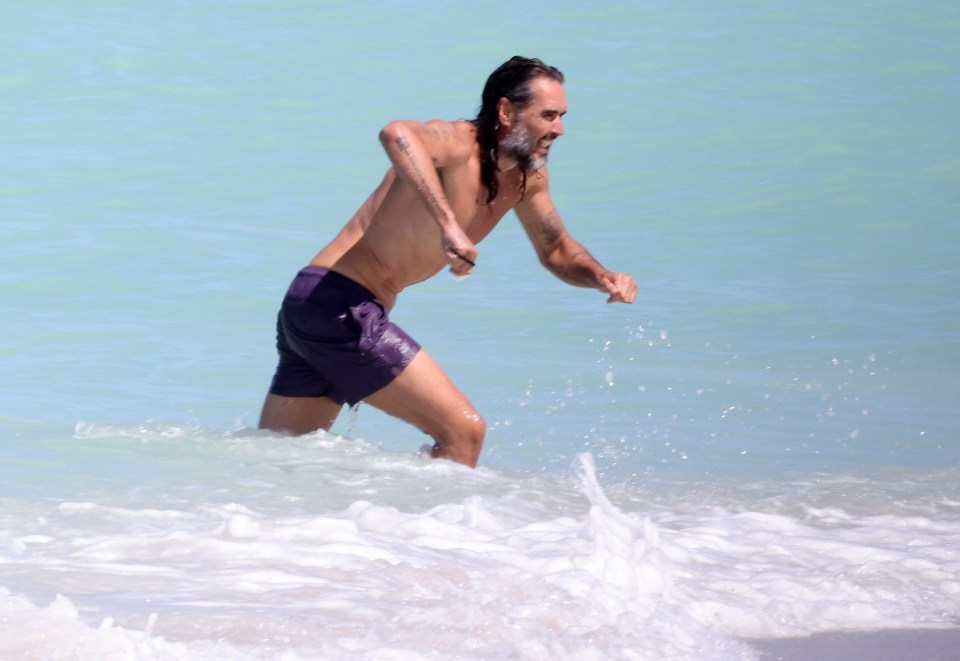 Russell Brand wading in the ocean.