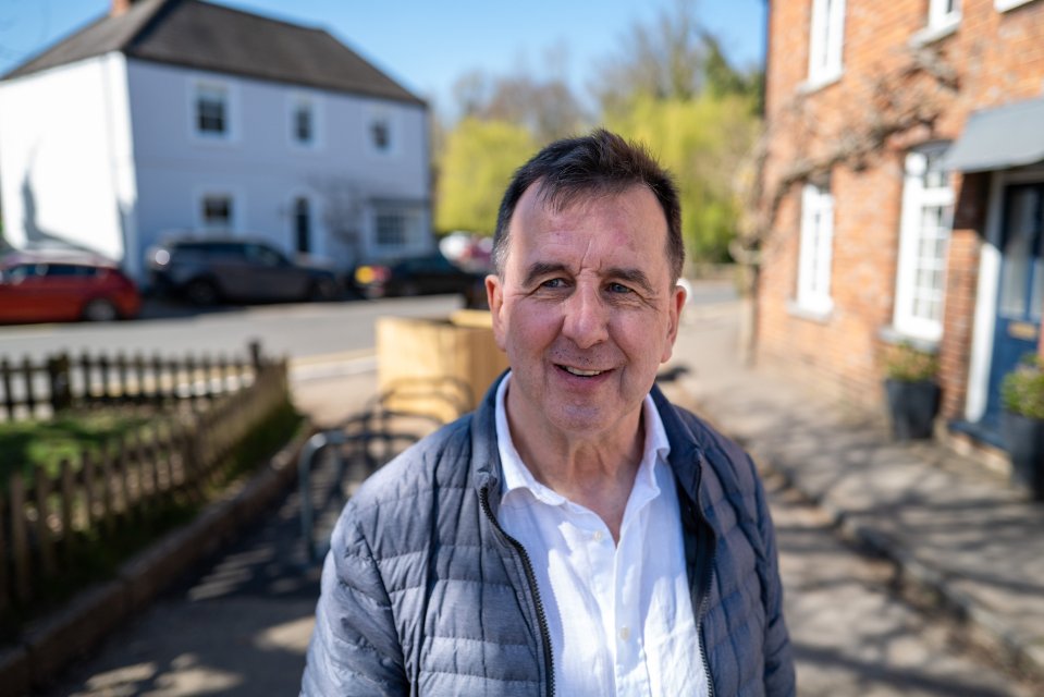 Portrait of a man smiling in front of houses.