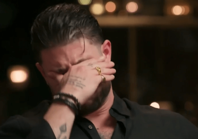 A man crying and covering his face with his hand.