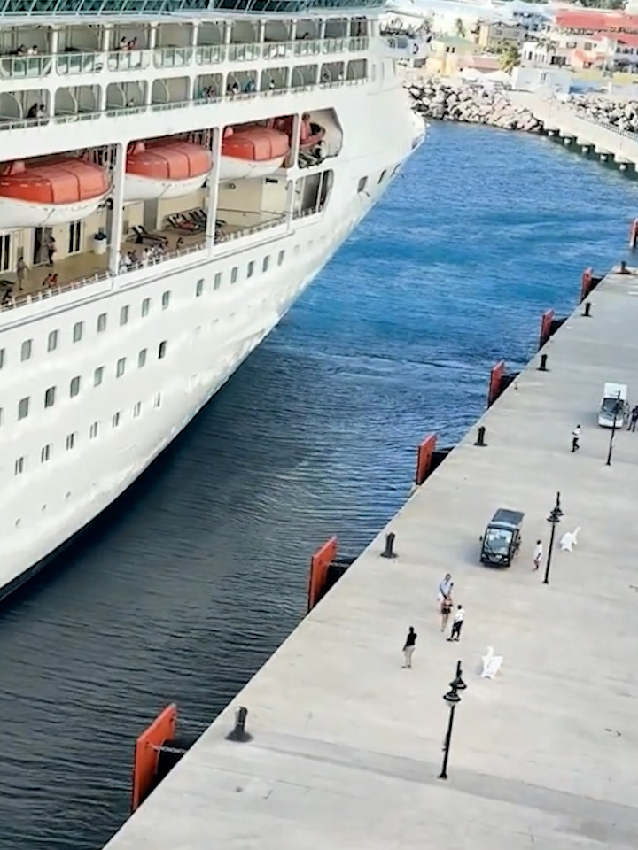 A cruise ship departing, leaving a couple behind on the dock.