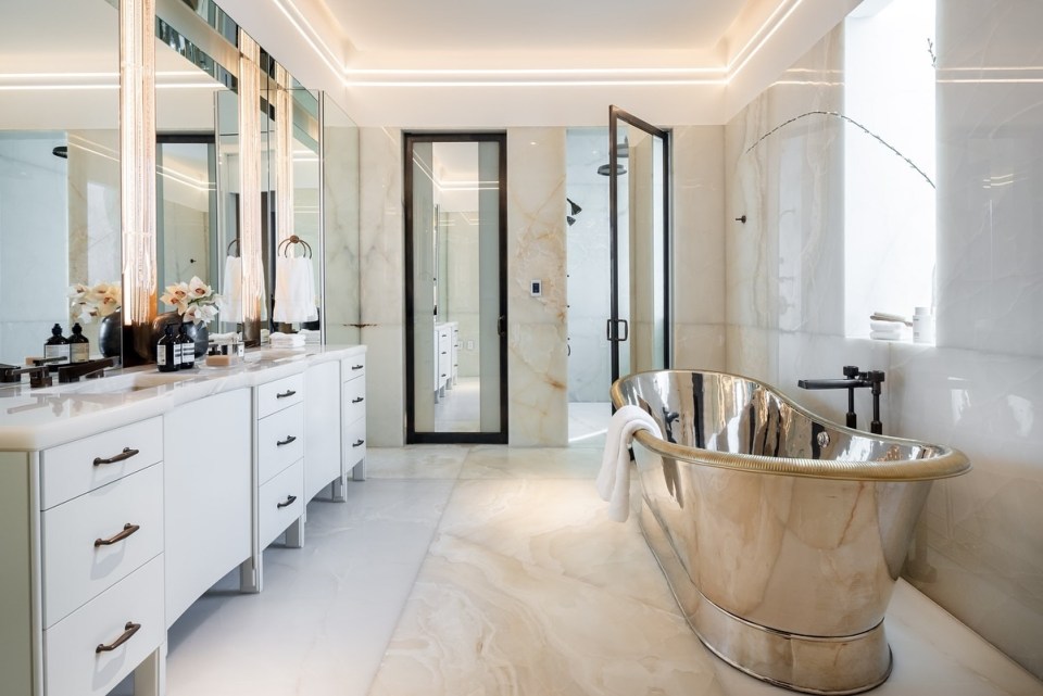 Luxurious bathroom with a freestanding silver bathtub and marble walls.