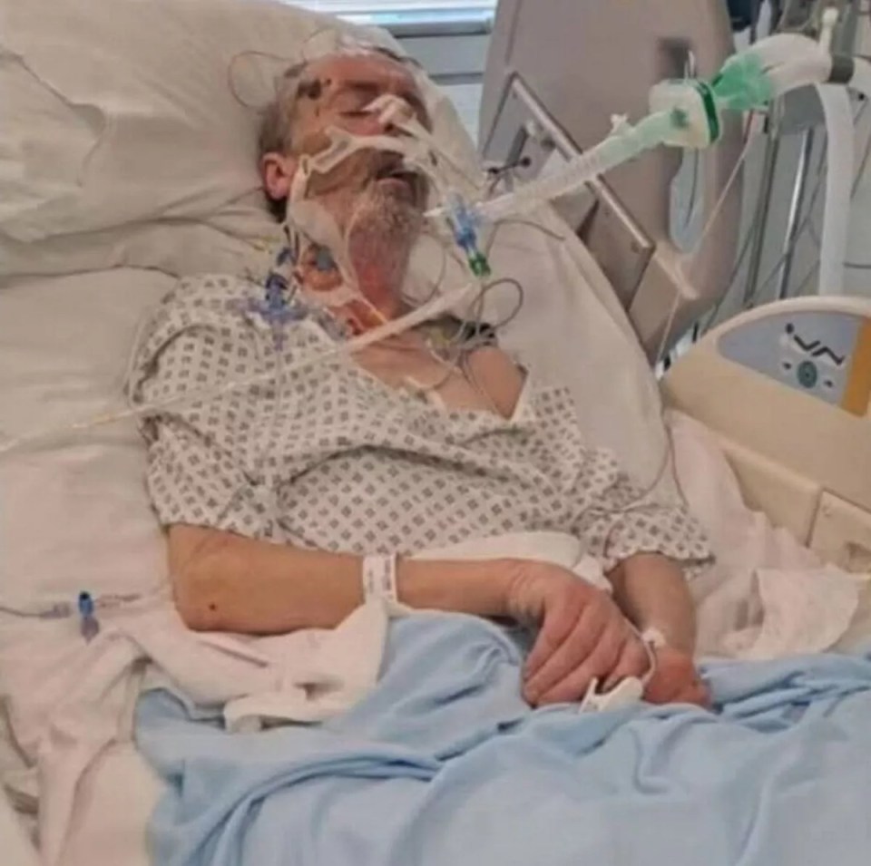 Man lying in a hospital bed, hooked up to medical equipment.