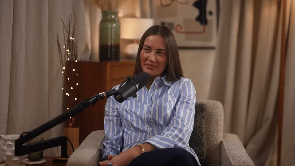 Woman sitting in a chair, speaking into a microphone during a podcast interview.