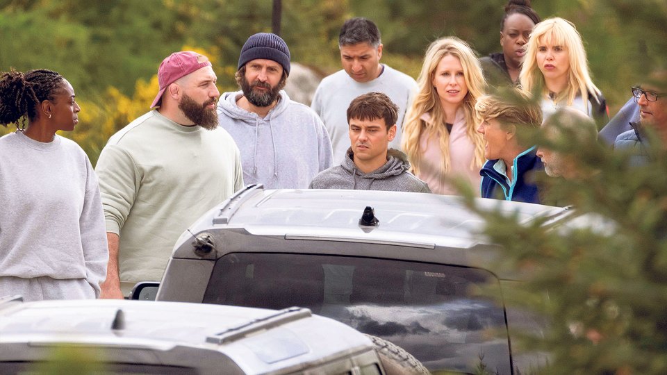 The Traitors cast members walking towards cars.