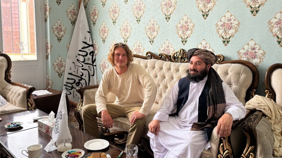 Two men sitting on a couch in a room.