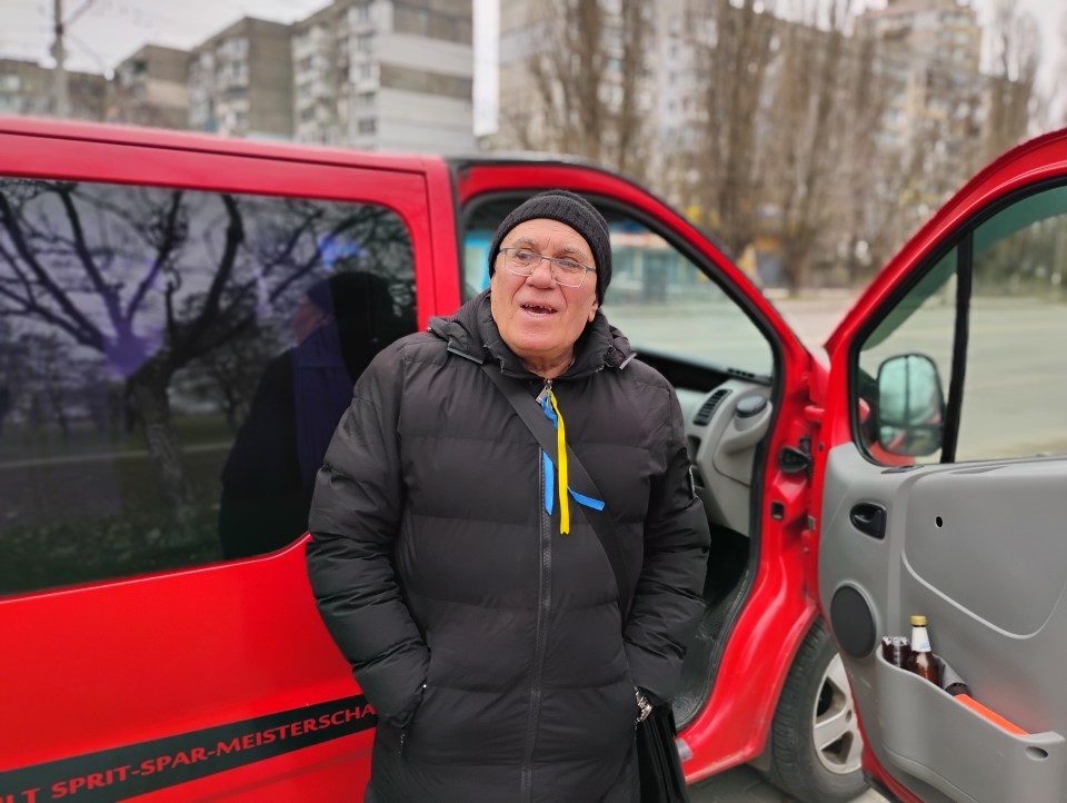 Coach Vyacheslav Roll standing by a red van.