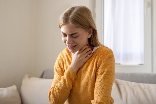 Woman holding her throat, appearing unwell.
