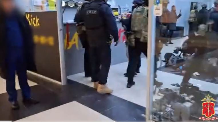 Russian police officers in a building, apparently apprehending men.
