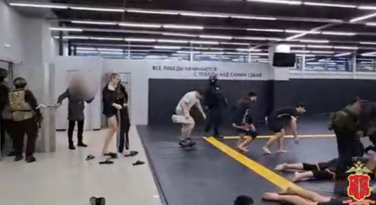 Russian police officers apprehending men in a gym.