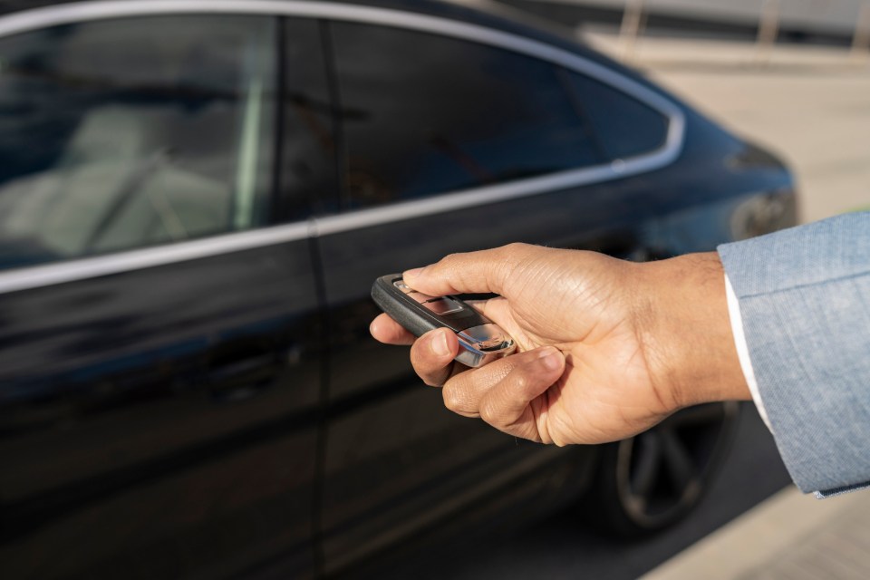 Person unlocking a car with a key fob.
