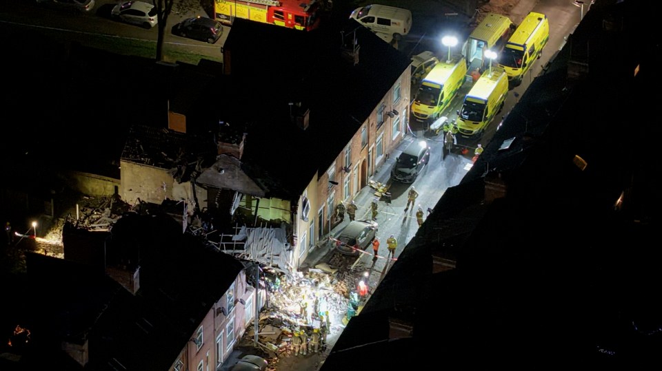 Aerial view of emergency services responding to a house explosion at night.