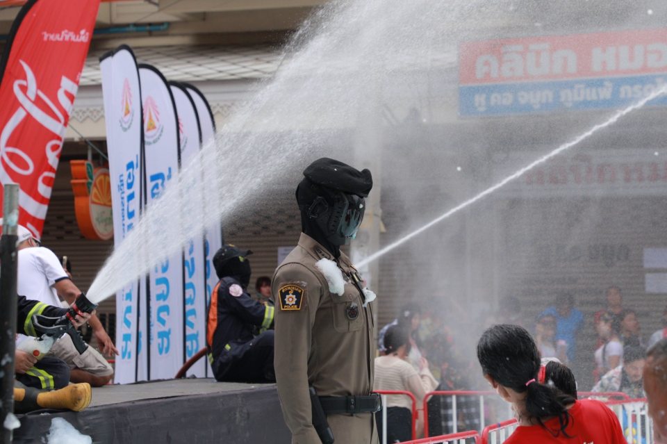 A robot police officer being sprayed with water.