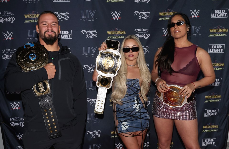 Bron Breakker, Liv Morgan, and Raquel Rodriguez holding their WWE championship belts.