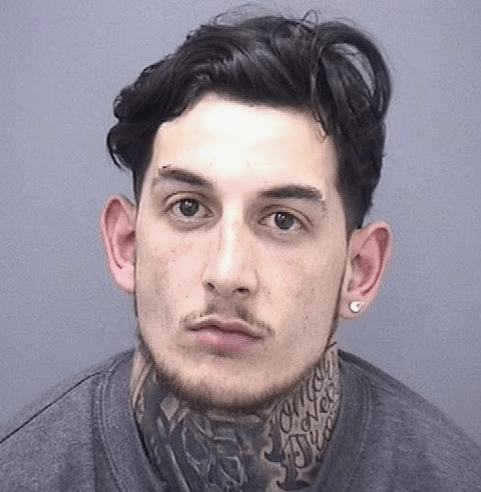 Mugshot of a man with dark hair and tattoos.