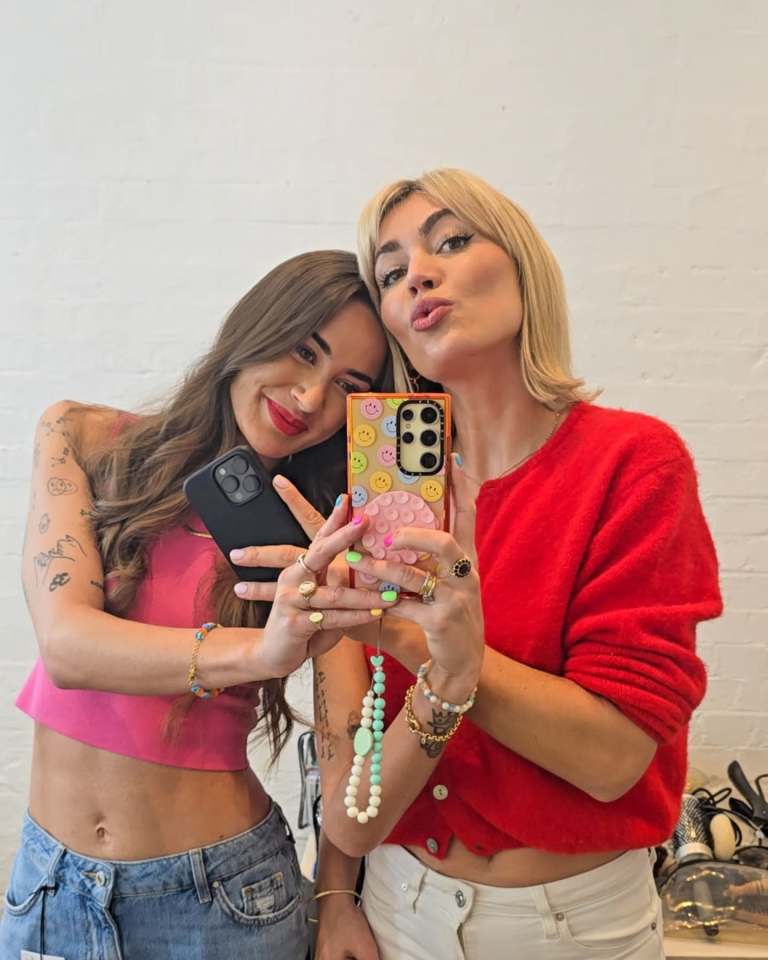 Two women taking a selfie with their phones.
