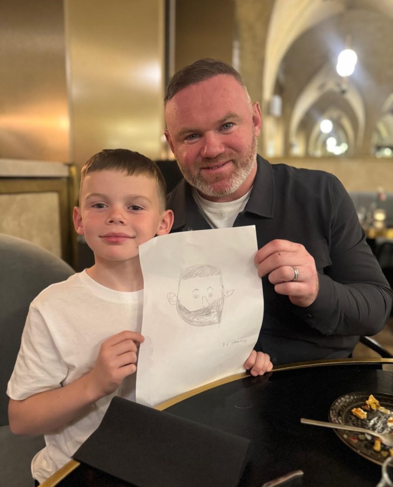 A boy shows his father a drawing of a man.