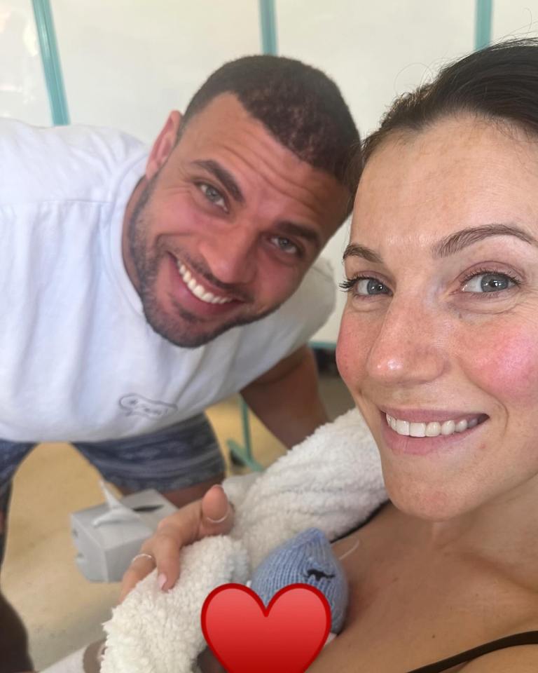 A happy couple holding their newborn baby.