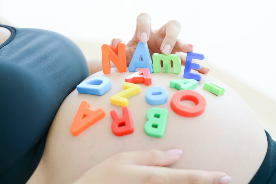 Pregnant woman's belly with colorful letter blocks spelling NAME.