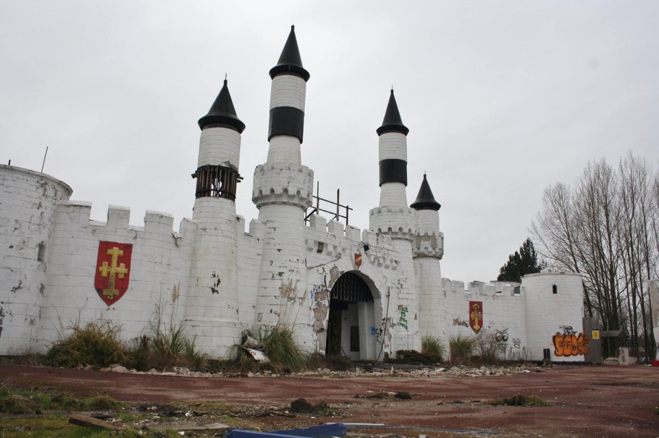 Graffiti-covered entrance to an abandoned Camelot-themed park.