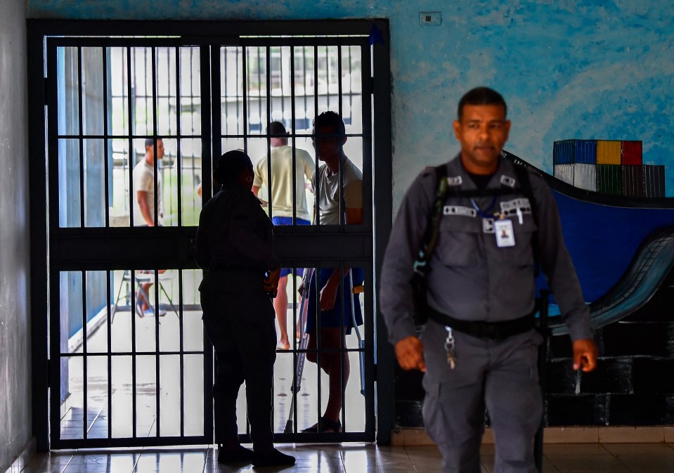 Inmate speaks with guard through prison bars.