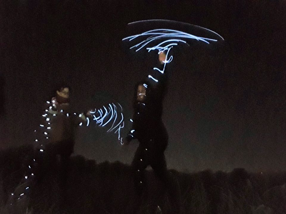 Photo of two sisters at night, using light painting to create abstract shapes.
