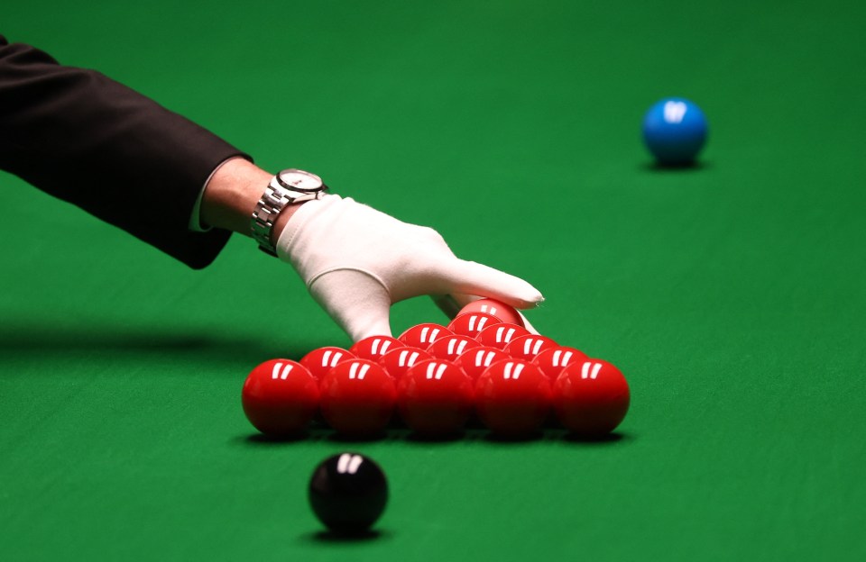 Referee placing snooker balls on the table.